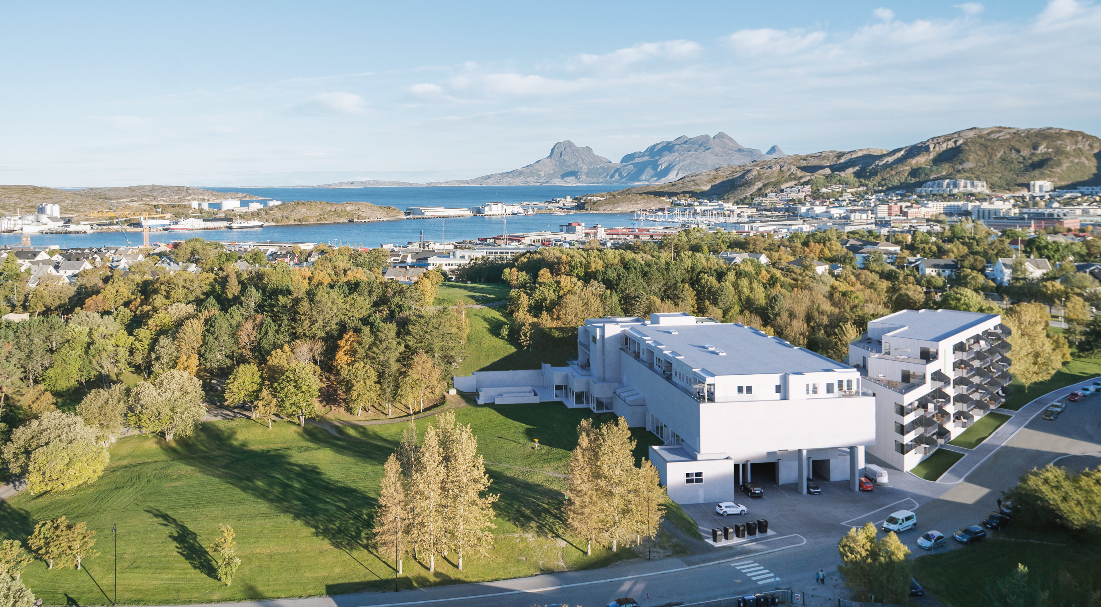 Et luftfoto av en hvit bygning med fjell i bakgrunnen, laget for Eiendomsmegler1 som en visuell representasjon for salgsformål i 2016.