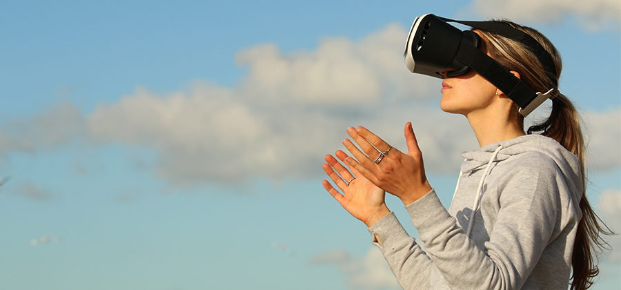 En kvinne som opplever VR-innlevelse med en fantastisk blå himmel i bakgrunnen.