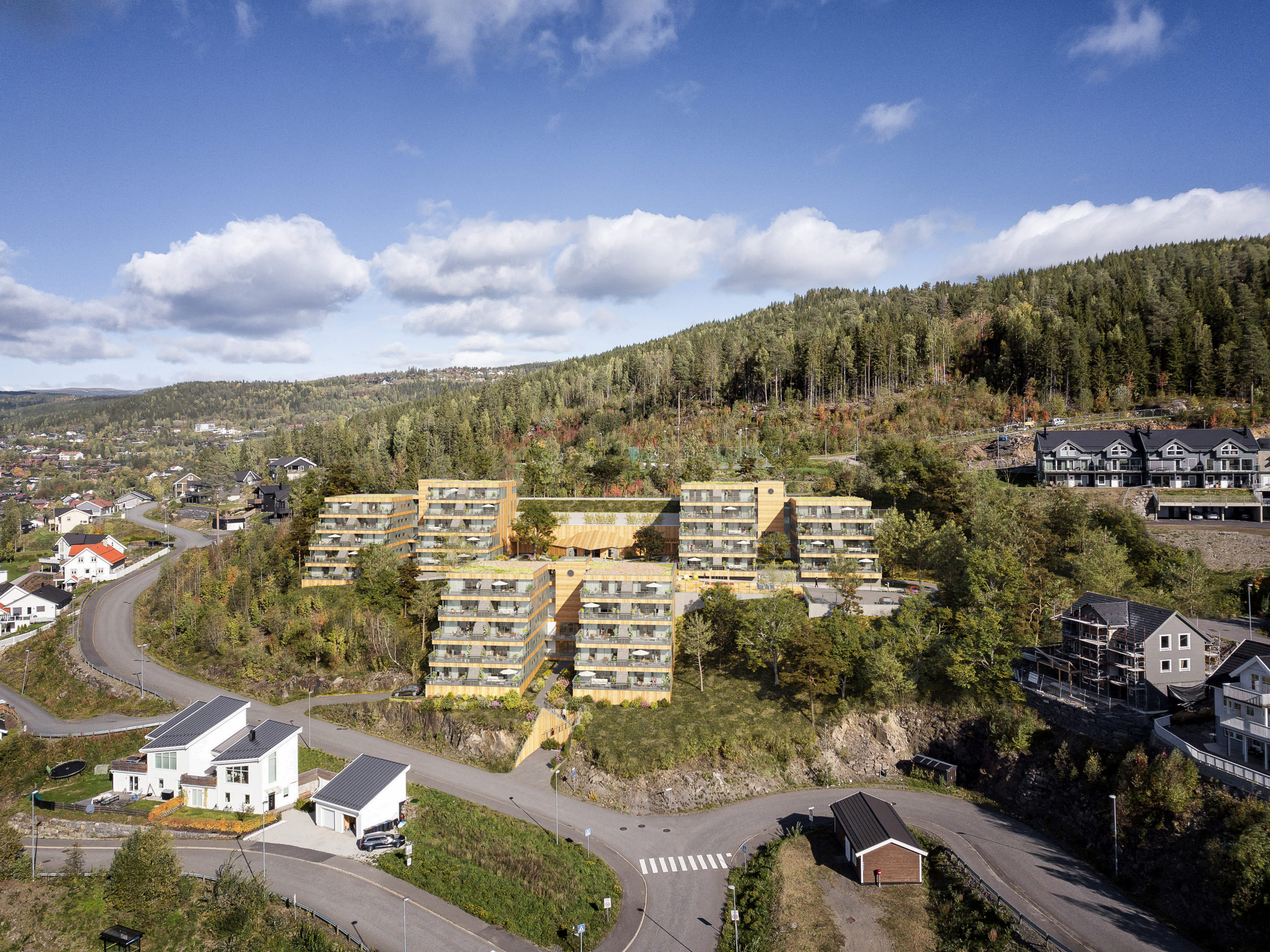 en luftfoto av et leilighetskompleks i et skogsområde.