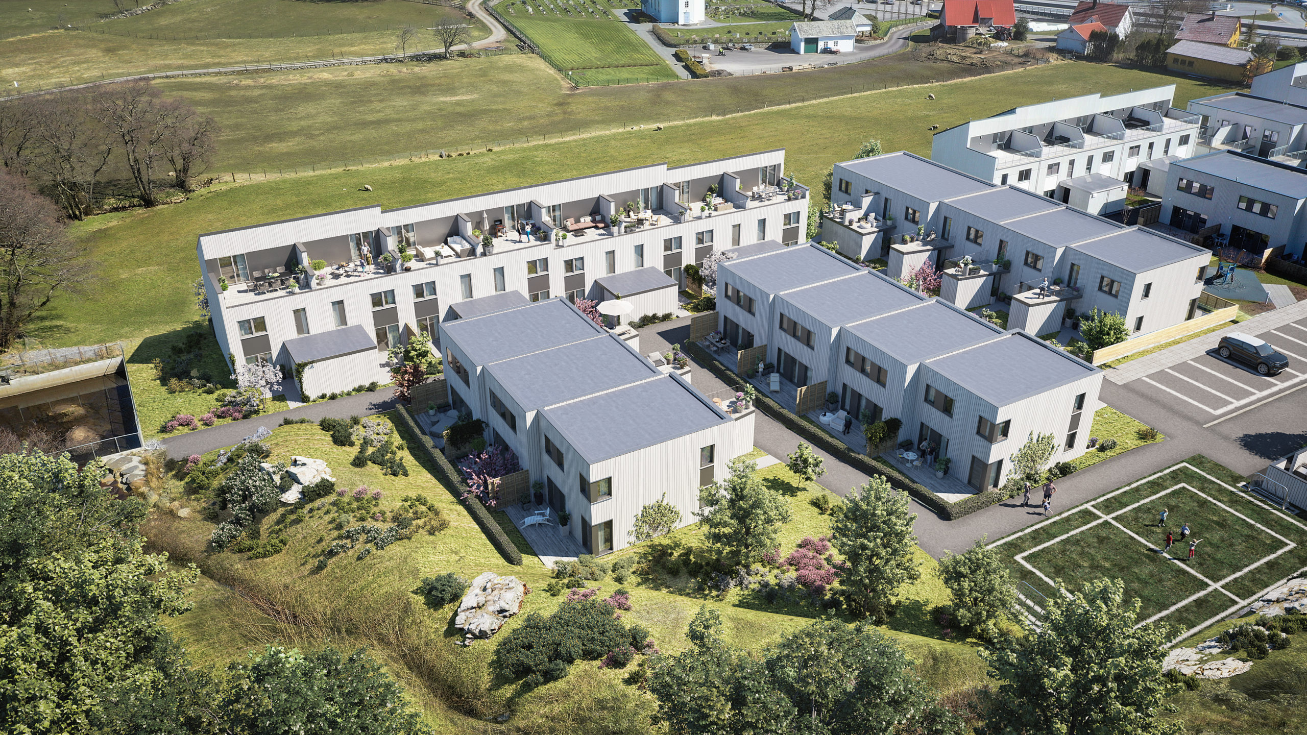 en luftfoto av et leilighetskompleks med en fotballbane i bakgrunnen.
