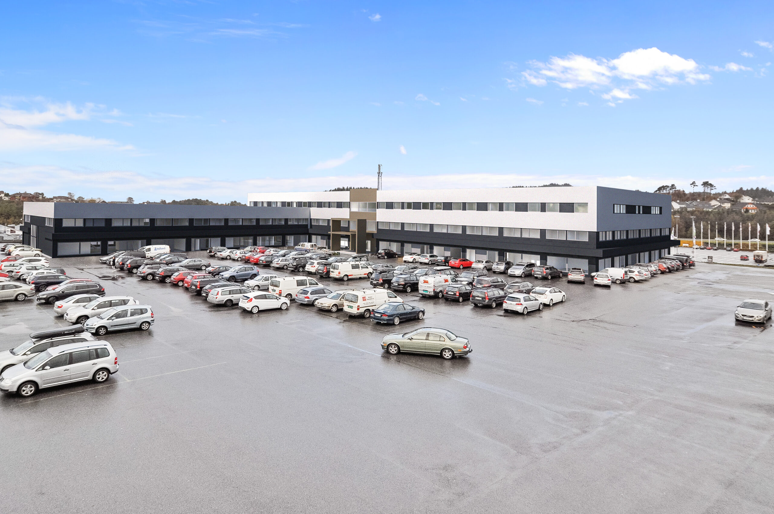et stort kontorbygg med biler parkert på parkeringsplassen.