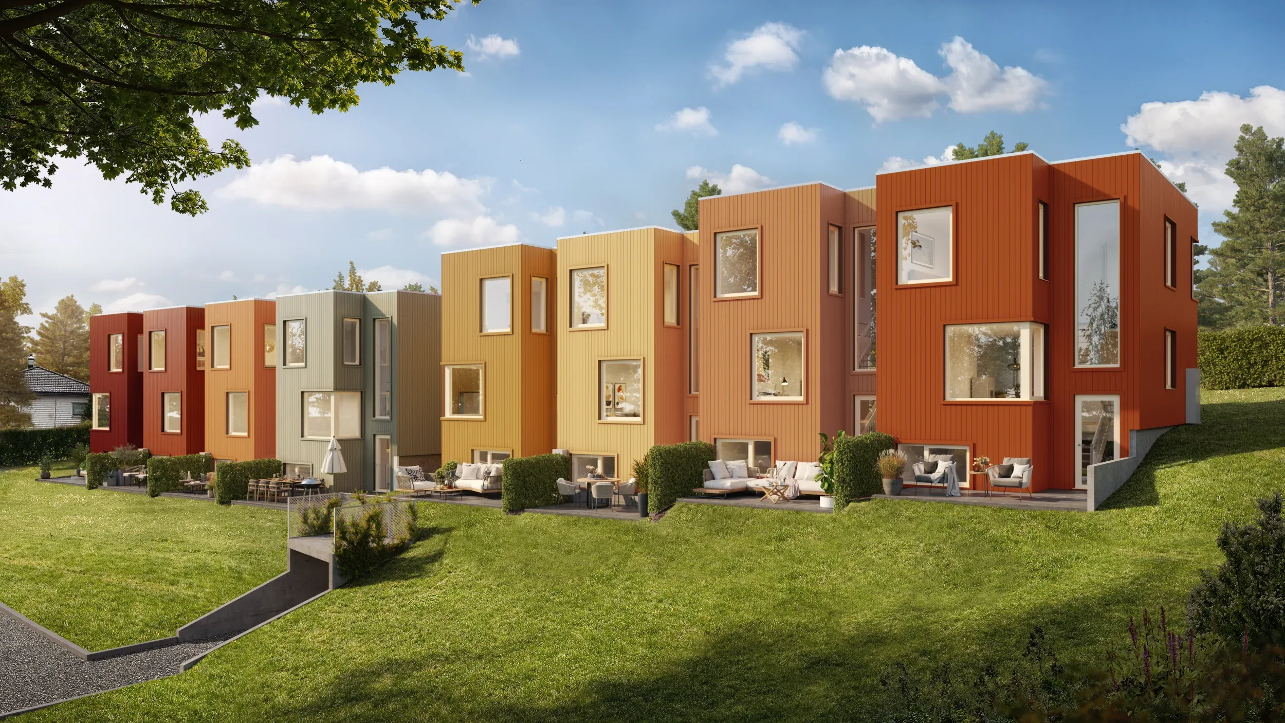 En rekke moderne, fargerike rekkehus med store vinduer og private uteplasser ligger på en gressbakke under en delvis overskyet himmel.